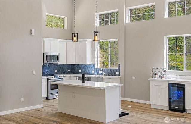 10642 Merry Canyon Rd, Leavenworth, WA 98820 - kitchen featuring stainless steel appliances, wine cooler, a towering ceiling, baseboards, and white cabinetry