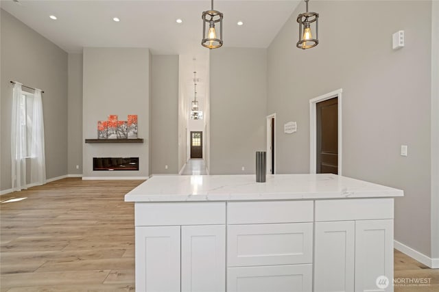 10642 Merry Canyon Rd, Leavenworth, WA 98820 - kitchen featuring white cabinetry, light wood finished floors, light stone countertops, baseboards, and a towering ceiling