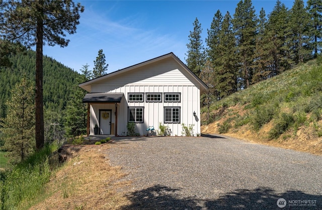 10642 Merry Canyon Rd, Leavenworth, WA 98820 - view of front of house featuring board and batten siding, a wooded view, and gravel driveway