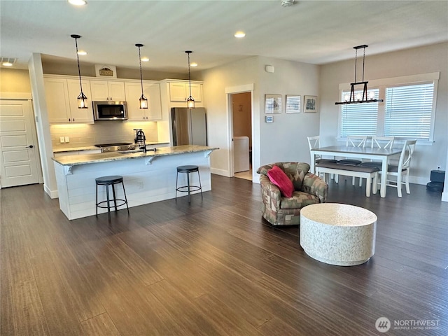 14091401 Diamond Head Ave SW, Ocean Shores, WA 98569 - kitchen featuring appliances with stainless steel finishes, a kitchen bar, light stone countertops, white cabinetry, and recessed lighting