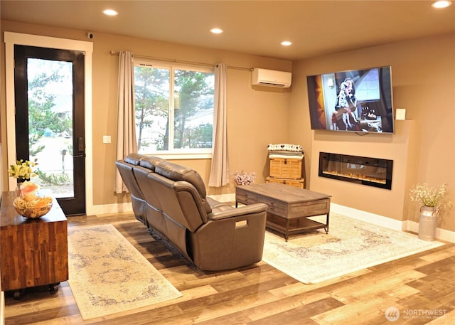 613 Aster Ct SE, Ocean Shores, WA 98569 - living room featuring a wall mounted air conditioner, recessed lighting, wood finished floors, baseboards, and a glass covered fireplace