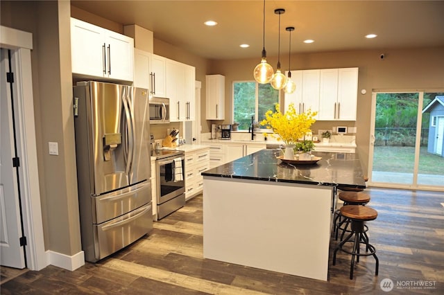 613 Aster Ct SE, Ocean Shores, WA 98569 - kitchen with stainless steel appliances, recessed lighting, a kitchen bar, plenty of natural light, and white cabinets