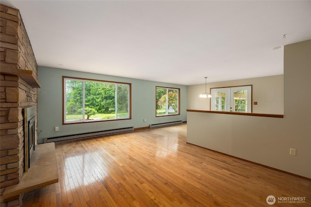 7823 Parker Rd, Sedro Woolley, WA 98284 - unfurnished living room with a baseboard heating unit, a stone fireplace, light wood-style flooring, and a chandelier