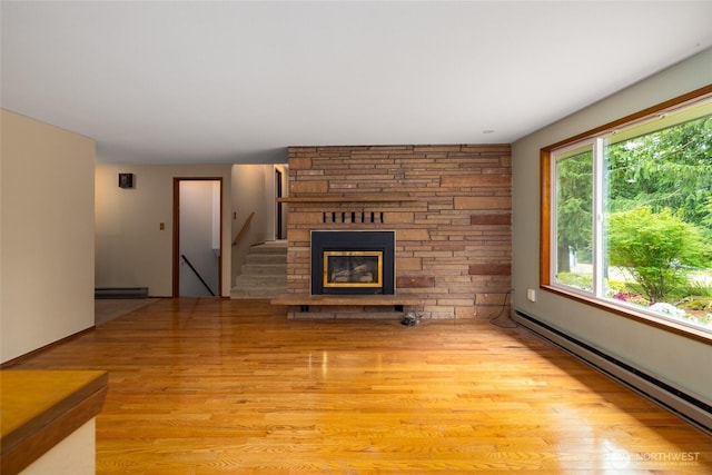7823 Parker Rd, Sedro Woolley, WA 98284 - unfurnished living room with a baseboard heating unit, light wood-style floors, a stone fireplace, and stairway