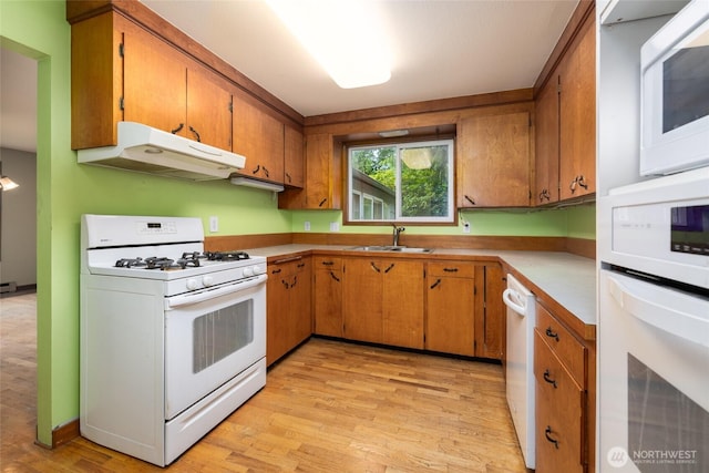 7823 Parker Rd, Sedro Woolley, WA 98284 - kitchen with white appliances, under cabinet range hood, light wood-style floors, brown cabinetry, and light countertops