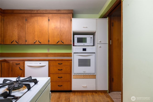 7823 Parker Rd, Sedro Woolley, WA 98284 - kitchen featuring white appliances, light wood-style floors, light countertops, and brown cabinetry