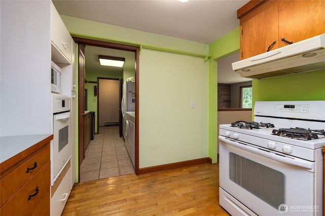 7823 Parker Rd, Sedro Woolley, WA 98284 - kitchen featuring white appliances, under cabinet range hood, light wood finished floors, and brown cabinets