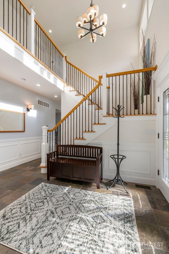 6817 Picnic Point Rd, Edmonds, WA 98026 - foyer entrance featuring a decorative wall, stone tile flooring, stairs, a chandelier, and a high ceiling