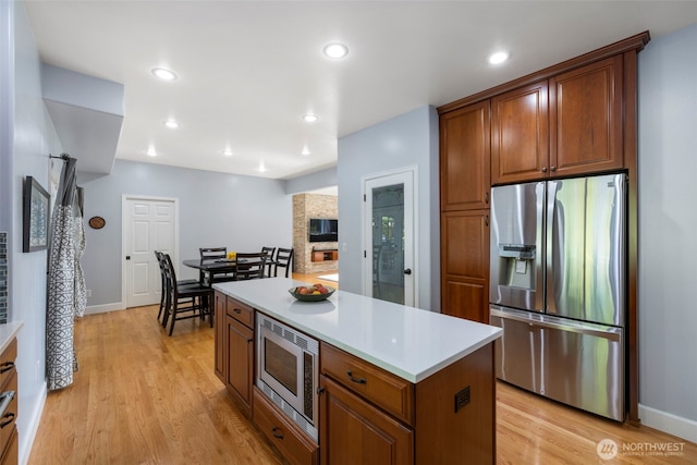 6817 Picnic Point Rd, Edmonds, WA 98026 - kitchen with appliances with stainless steel finishes, light wood finished floors, light countertops, a fireplace, and recessed lighting