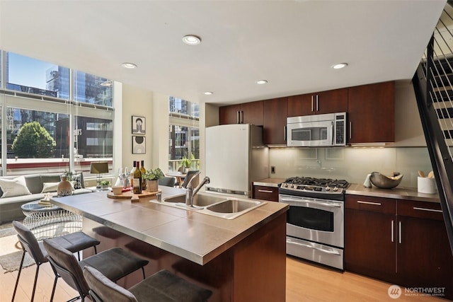 900 Lenora St Unit W106, Seattle, WA 98121 - kitchen with appliances with stainless steel finishes, a breakfast bar area, light wood finished floors, recessed lighting, and dark brown cabinetry