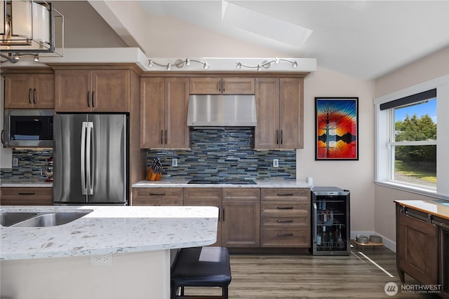 24 Jacalyn Ln, Grayland, WA 98547 - kitchen featuring appliances with stainless steel finishes, under cabinet range hood, vaulted ceiling, backsplash, and wood finished floors