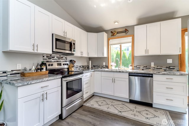 6002 35th Way SE, Auburn, WA 98092 - kitchen featuring appliances with stainless steel finishes, lofted ceiling, backsplash, white cabinets, and wood finished floors