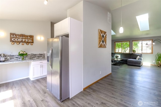 6002 35th Way SE, Auburn, WA 98092 - kitchen with stainless steel refrigerator with ice dispenser, a skylight, white cabinets, light wood-style floors, and vaulted ceiling