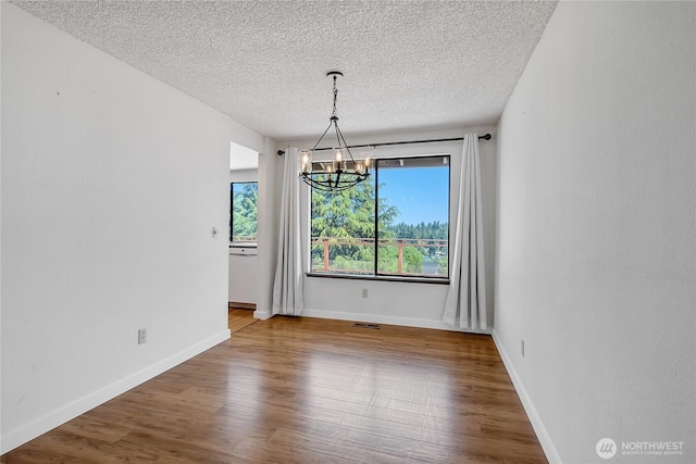 4026 SW 328th St, Federal Way, WA 98023 - unfurnished dining area featuring a chandelier, plenty of natural light, a textured ceiling, and wood finished floors
