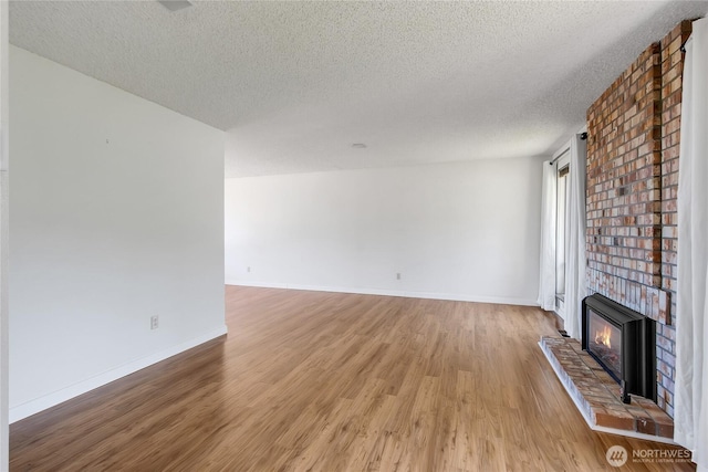 4026 SW 328th St, Federal Way, WA 98023 - unfurnished living room with a textured ceiling, light wood-type flooring, and a brick fireplace