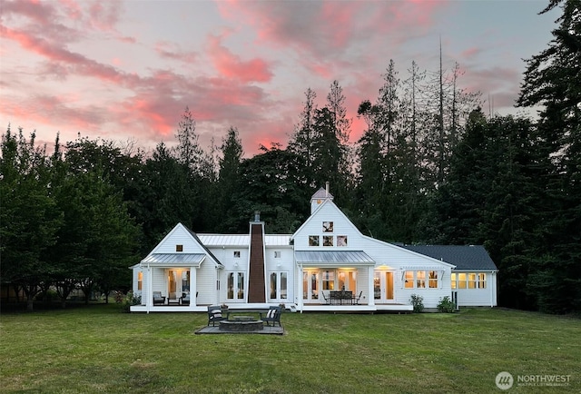 2575 Bretland Rd, Camano Island, WA 98282 - back of house at dusk with a fire pit, french doors, a yard, and a standing seam roof