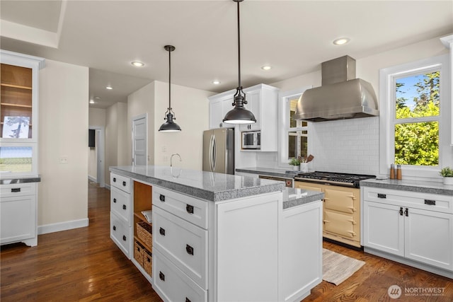 2575 Bretland Rd, Camano Island, WA 98282 - kitchen featuring appliances with stainless steel finishes, exhaust hood, an island with sink, tasteful backsplash, and dark wood-style floors