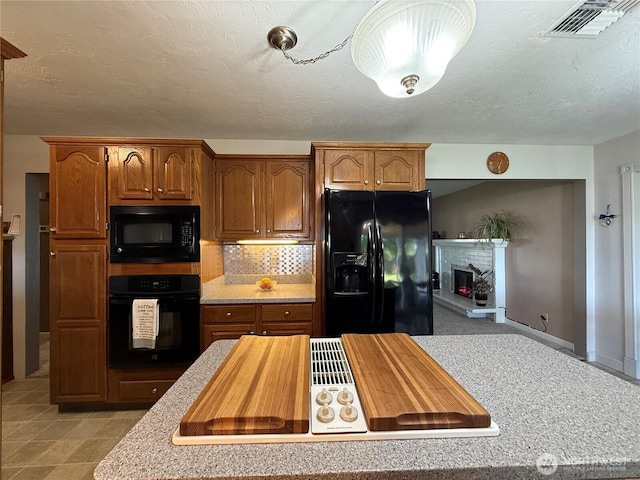 4208 W Okanogan Ave, Kennewick, WA 99336 - kitchen featuring black appliances, a warm lit fireplace, backsplash, brown cabinets, and baseboards
