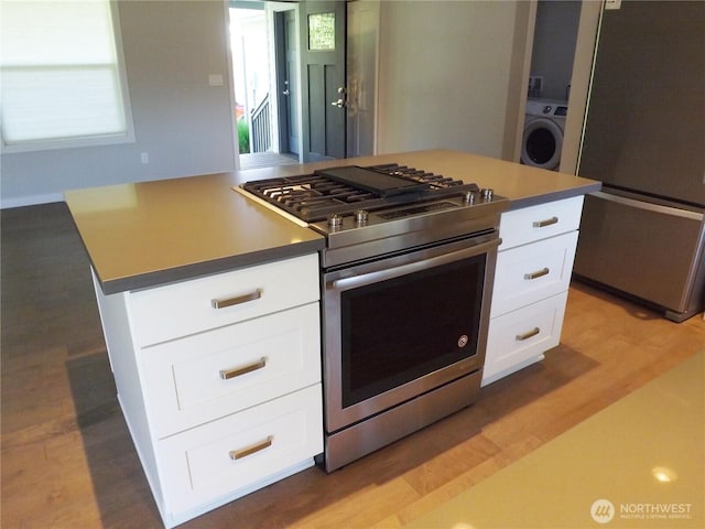 2568 Myra Pl, Langley, WA 98260 - kitchen with appliances with stainless steel finishes, washer / clothes dryer, white cabinets, and light wood-style floors