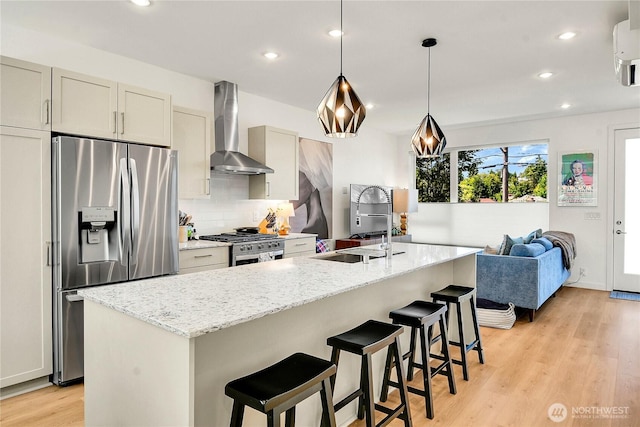 3815 S Cloverdale St, Seattle, WA 98118 - kitchen with wall chimney exhaust hood, appliances with stainless steel finishes, light wood-style flooring, decorative backsplash, and a center island with sink