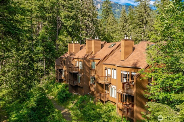 10500 Mt Baker Hwy Unit 905, Deming, WA 98244 - rear view of property featuring a chimney, a shingled roof, a wooded view, and a balcony