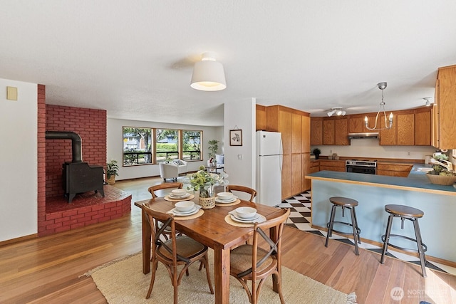 1443 U St, Port Townsend, WA 98368 - dining room featuring a wood stove, light wood-type flooring, and a chandelier