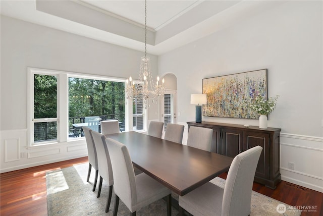 7531 Hawkstone Ave SW, Port Orchard, WA 98367 - dining space with a chandelier, wood finished floors, a wainscoted wall, arched walkways, and a decorative wall