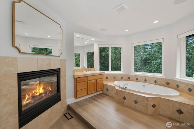 7531 Hawkstone Ave SW, Port Orchard, WA 98367 - bathroom featuring vanity, a jetted tub, a fireplace, wood finished floors, and recessed lighting