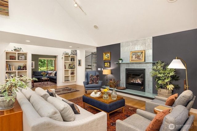 9000 NE Hidden Cove Rd, Bainbridge Island, WA 98110 - living room featuring wood finished floors, a tile fireplace, stairs, and high vaulted ceiling