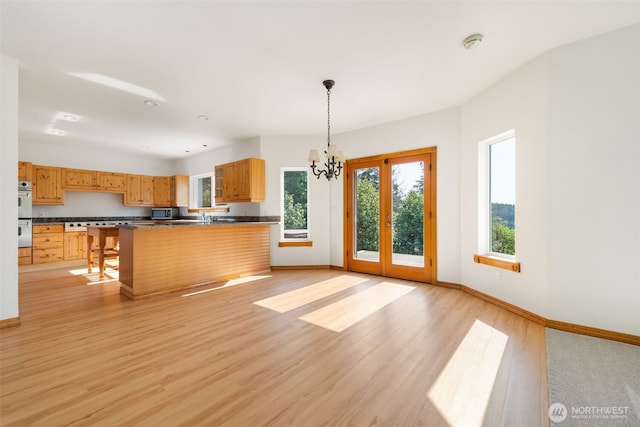 14502 45th St SW, Lakebay, WA 98349 - kitchen featuring dark countertops, light wood-type flooring, baseboards, pendant lighting, and a chandelier