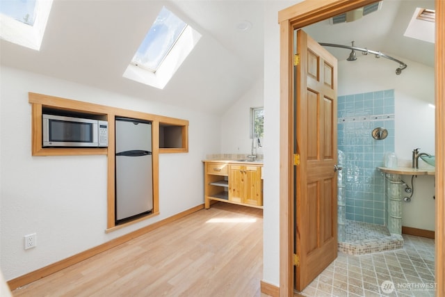 14502 45th St SW, Lakebay, WA 98349 - full bathroom featuring a skylight, a tile shower, lofted ceiling, wood finished floors, and baseboards