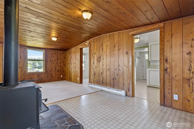 967 High Rd, Camano Island, WA 98282 - interior space featuring baseboard heating, a wood stove, wooden ceiling, light flooring, and wood walls