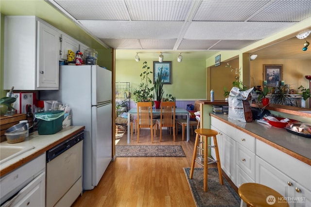 12421 2nd Ave S, Seattle, WA 98168 - kitchen with white appliances, light wood-style floors, white cabinetry, track lighting, and a wainscoted wall