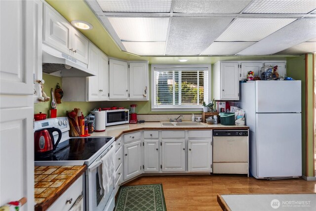 12421 2nd Ave S, Seattle, WA 98168 - kitchen featuring white appliances, under cabinet range hood, white cabinetry, and light wood-style flooring