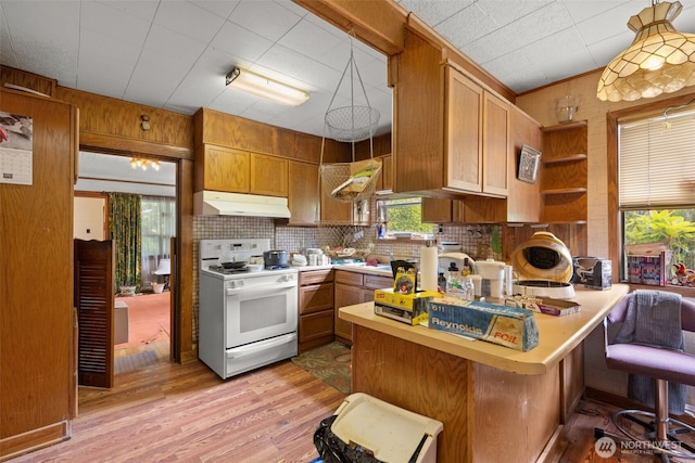 3626 E J St, Tacoma, WA 98404 - kitchen featuring white range oven, under cabinet range hood, a peninsula, light wood finished floors, and decorative backsplash