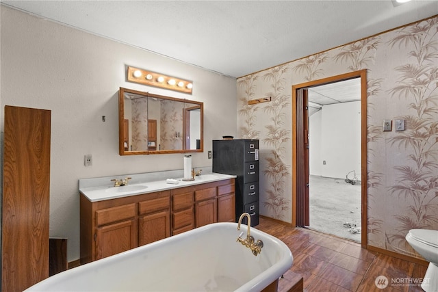 3626 E J St, Tacoma, WA 98404 - bathroom featuring a freestanding bath, double vanity, wallpapered walls, and wood finished floors