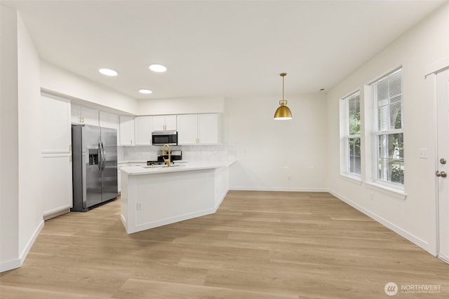 717 115th St E, Tacoma, WA 98445 - kitchen with stainless steel appliances, a peninsula, white cabinets, light countertops, and backsplash