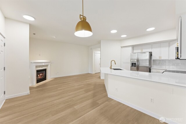 717 115th St E, Tacoma, WA 98445 - kitchen featuring stainless steel fridge with ice dispenser, a peninsula, light wood-style floors, white cabinets, and light countertops