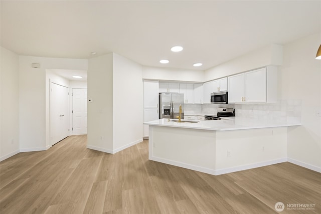 717 115th St E, Tacoma, WA 98445 - kitchen featuring appliances with stainless steel finishes, light wood finished floors, light countertops, tasteful backsplash, and a peninsula