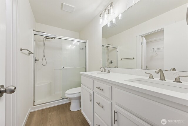 717 115th St E, Tacoma, WA 98445 - bathroom with wood finished floors, a stall shower, double vanity, and a walk in closet