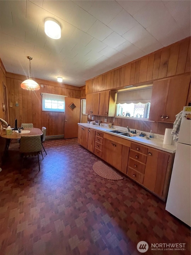 1204 Howard St, Raymond, WA 98577 - kitchen featuring a sink, wooden walls, brown cabinetry, light countertops, and freestanding refrigerator
