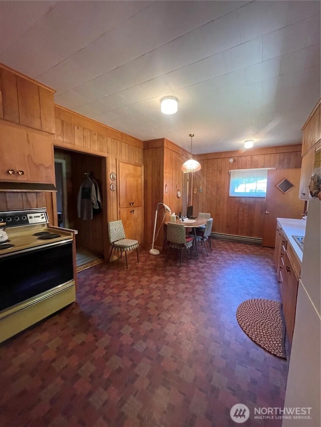 1204 Howard St, Raymond, WA 98577 - kitchen featuring white electric range oven, wooden walls, brown cabinets, light countertops, and hanging light fixtures