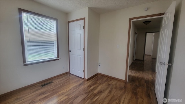 1618 112th St S, Parkland, WA 98444 - unfurnished bedroom with wood finished floors, multiple windows, and a textured ceiling