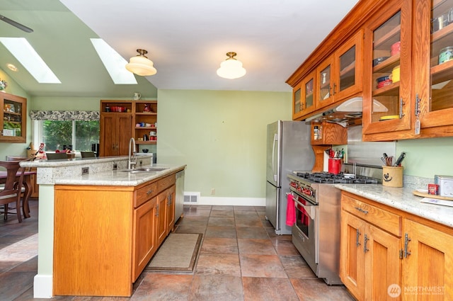 1833 3rd Ave, Kirkland, WA 98033 - kitchen featuring stainless steel appliances, a skylight, a center island with sink, brown cabinets, and light stone countertops