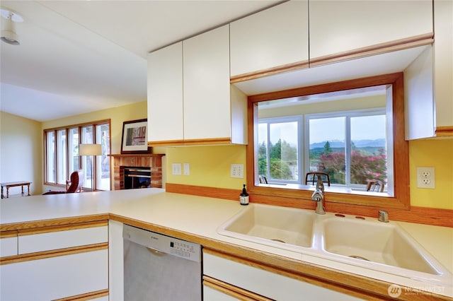 20135 Bue Rund Loop NE, Poulsbo, WA 98370 - kitchen featuring dishwasher, a sink, white cabinetry, a brick fireplace, and light countertops