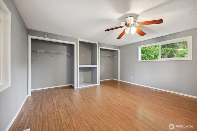 6836 Husky Way SE, Olympia, WA 98503 - unfurnished bedroom featuring two closets, wood finished floors, and ceiling fan