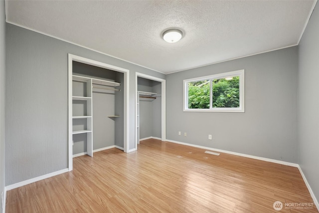 6836 Husky Way SE, Olympia, WA 98503 - unfurnished bedroom with light wood-style floors, multiple closets, a textured ceiling, and crown molding