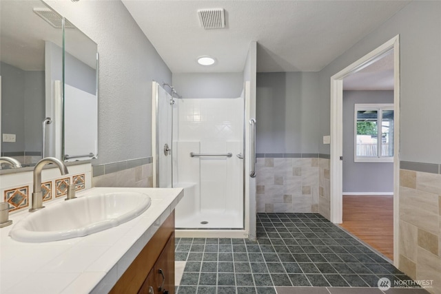 6836 Husky Way SE, Olympia, WA 98503 - full bathroom with tile walls, vanity, a shower stall, a wainscoted wall, and tile patterned floors