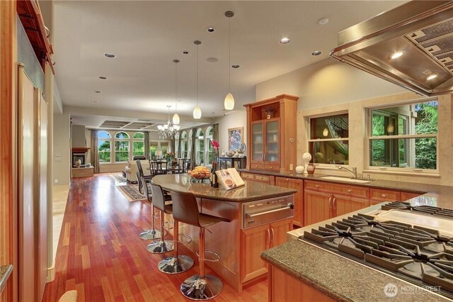 1055 91st Ave NE, Bellevue, WA 98004 - kitchen with stovetop, wall chimney range hood, a warming drawer, a sink, and a center island