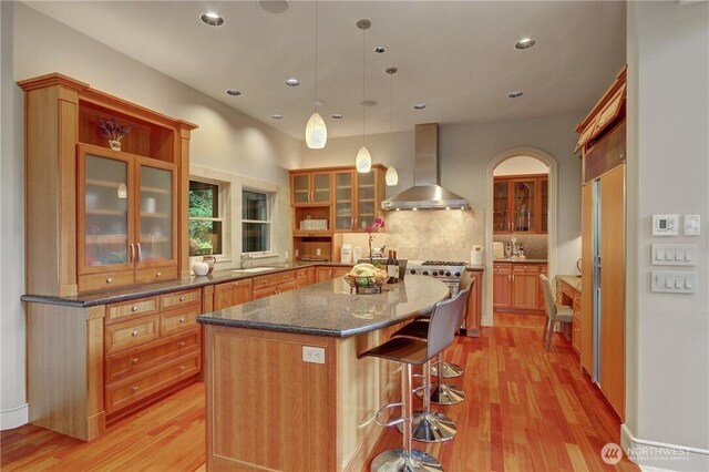 1055 91st Ave NE, Bellevue, WA 98004 - kitchen with wall chimney exhaust hood, light wood finished floors, a center island, glass insert cabinets, and recessed lighting